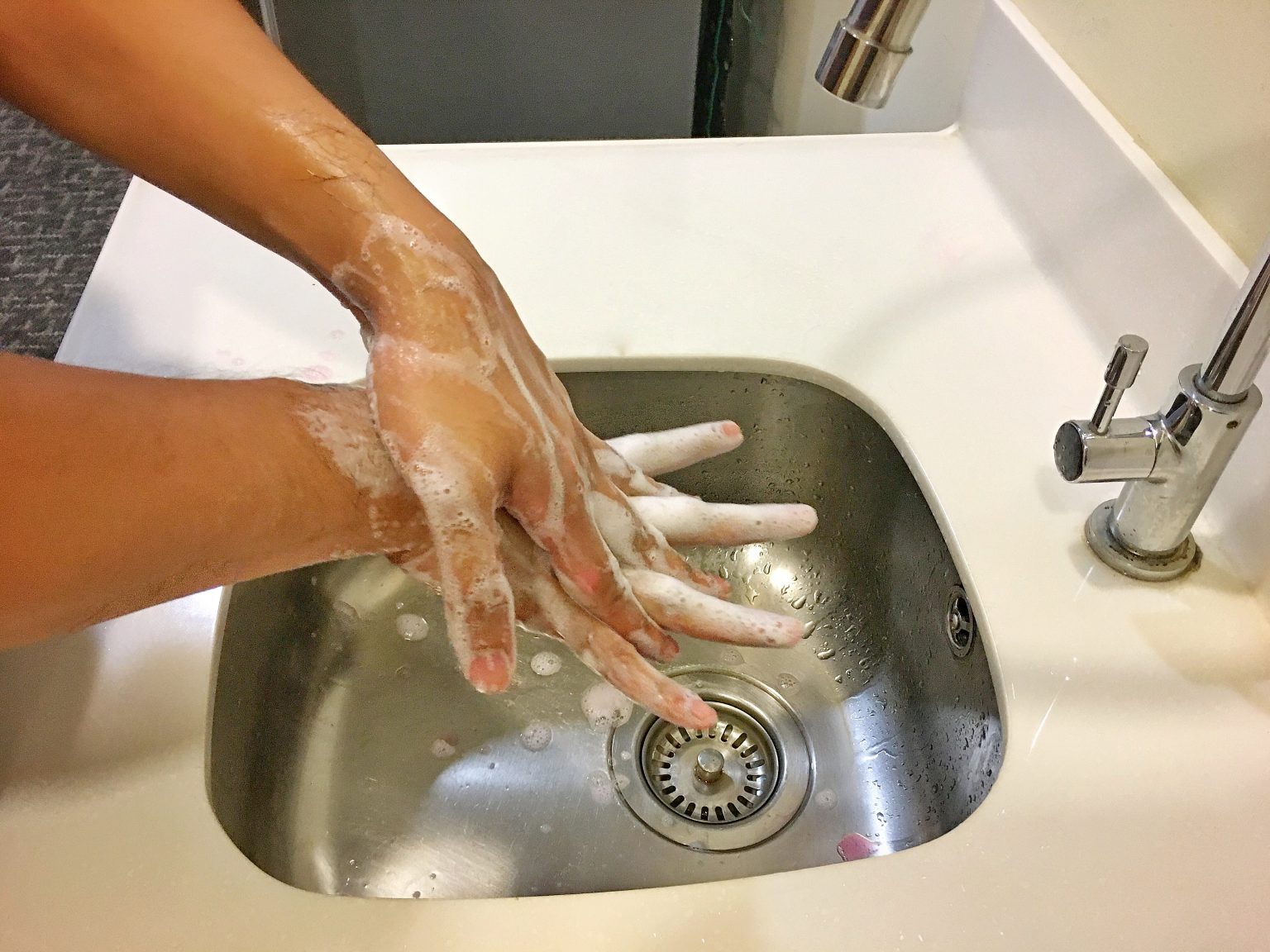 Close up shot of individual washing their hands to demonstrate the in-depth hand washing steps provided by the CDC.